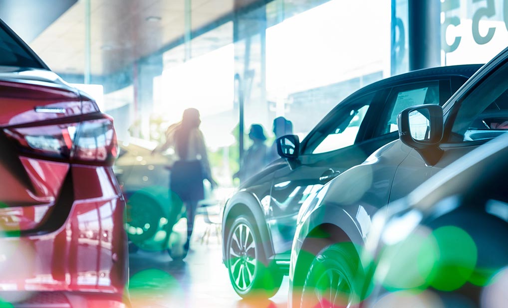 A group of individuals speaking on a car showroom floor