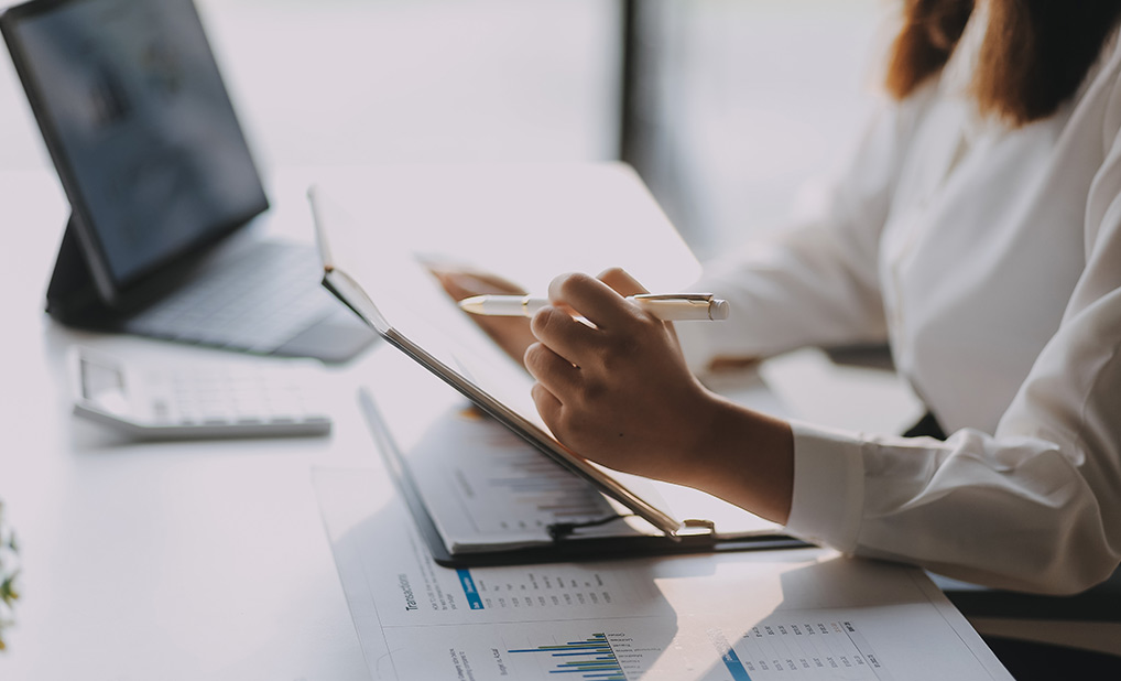 Person at desk holding pen and looking at documents