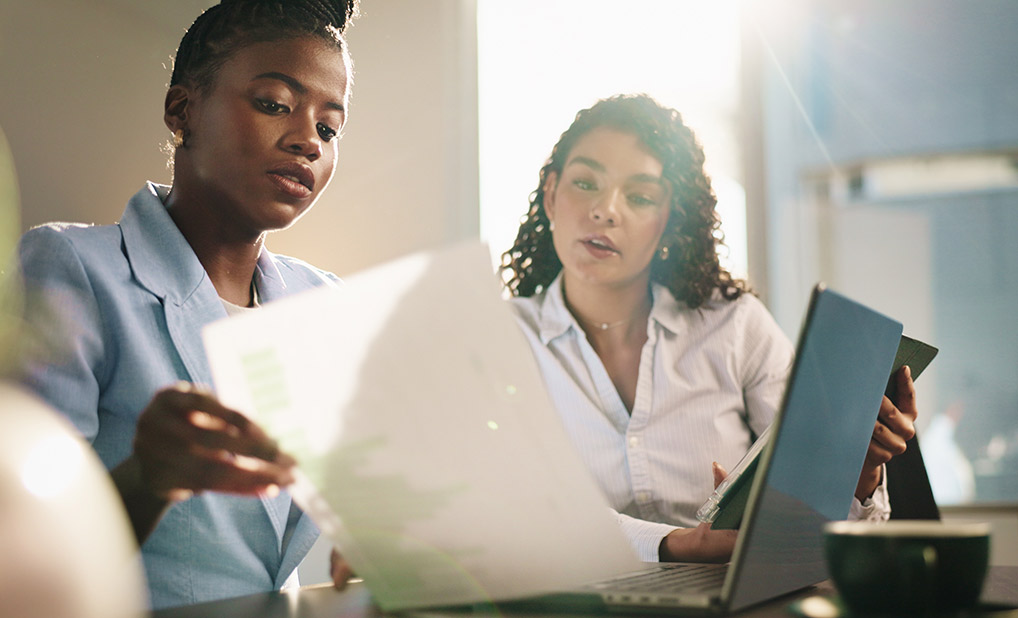 Two businesspeople looking at paper and computer together