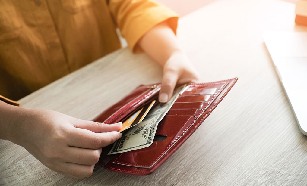 Close up of person holding wallet containing credit card and cash
