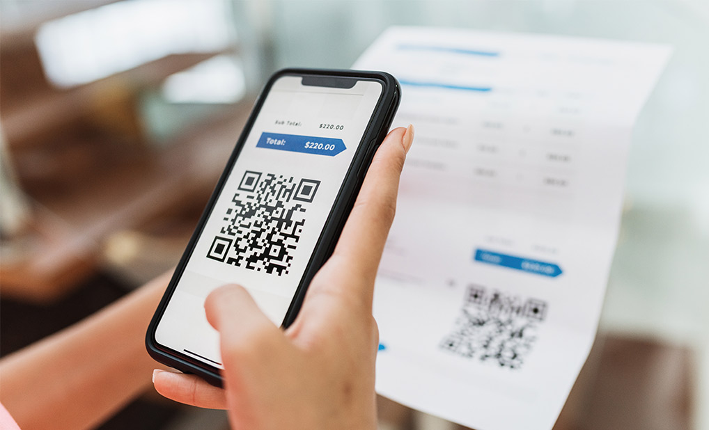 Close up of person using phone to scan QR code on bill