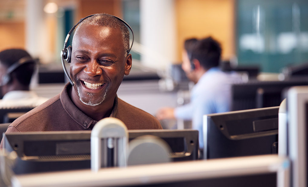 Person wearing headset and smiling at computer screen