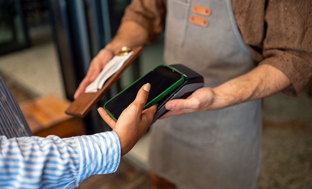 Close up of person using phone to pay at restaurant