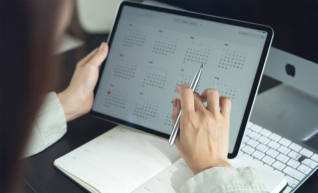 Close up of person using tablet displaying monthly calendar