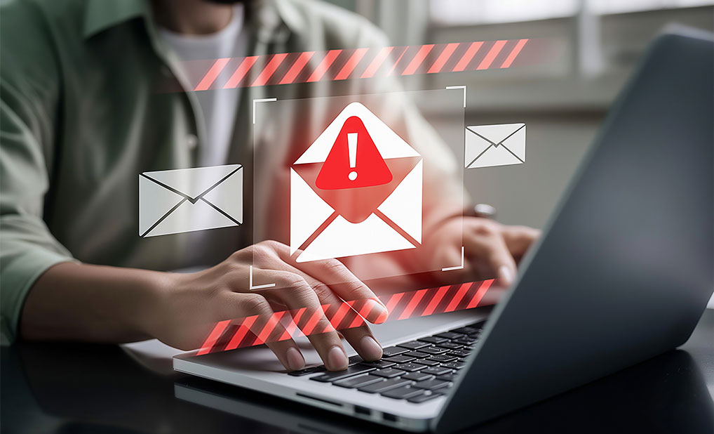 Person typing on computer with overlay of alert symbol