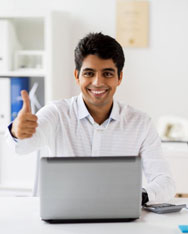A man using a laptop gives a thumbs-up