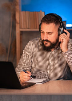 A man is listening headphone and taking notes
