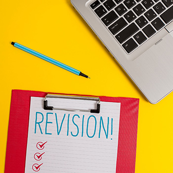 notepad with the word revision written on it next to laptop