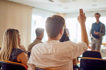 Man with his hand raised to ask a question