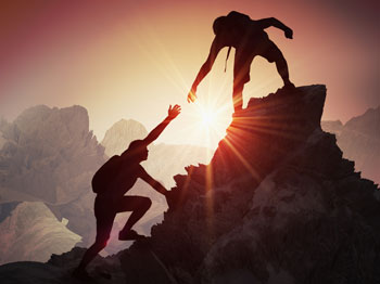 A climber at the top of a mountain reached out his hand to help another climber