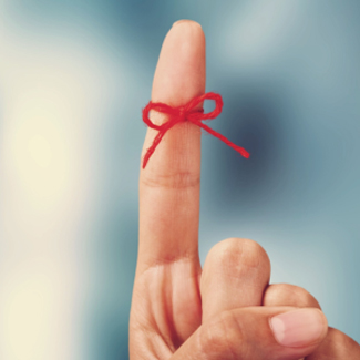 finger with red yarn tied around it