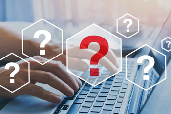 Questions marks overlayed on top of a picture of a person typing on a laptop