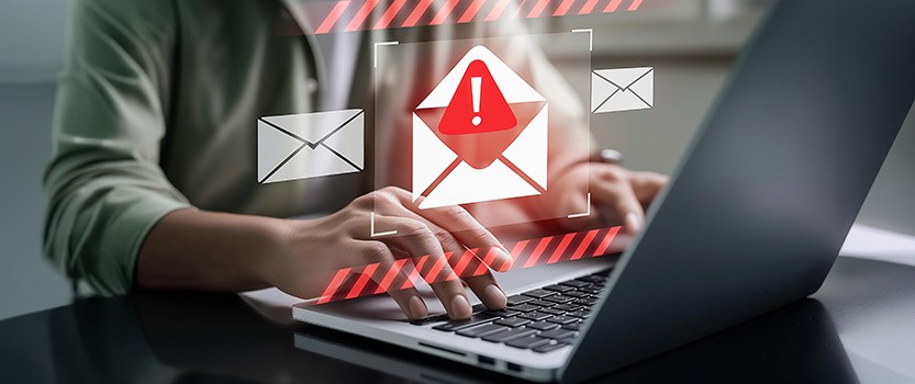 Person typing on computer with overlay of alert symbol