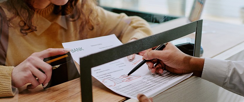 bank teller circling sheet of paper with pen for customer