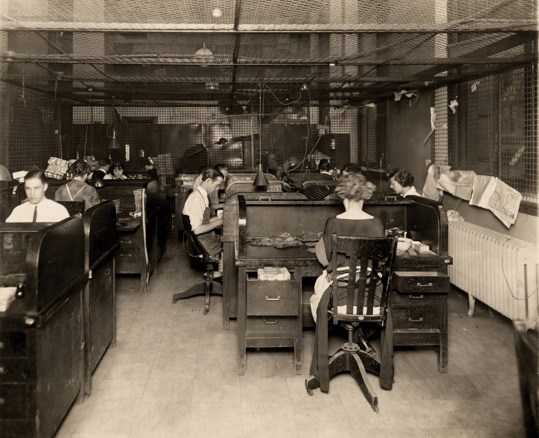 A group of men and women from the early 1900s sorting cash
