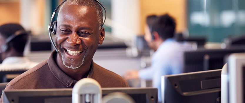 Person wearing headset and smiling at computer screen