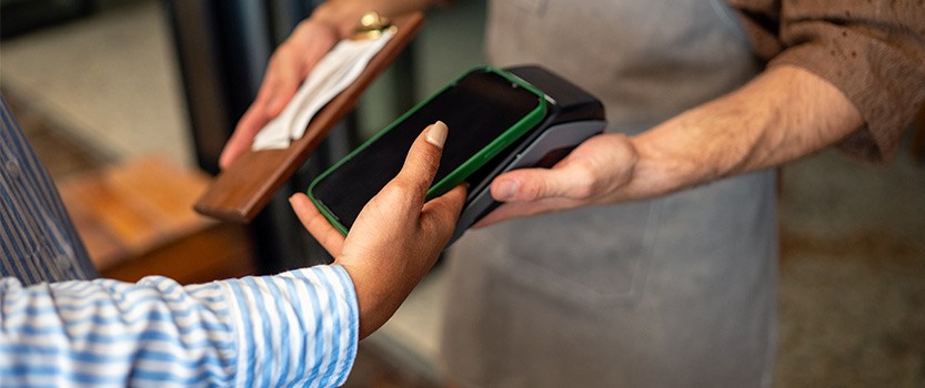 Close up of person using phone to pay at restaurant