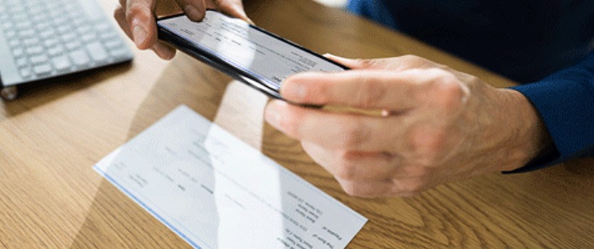 Person using a smartphone to take a picture of a physical check