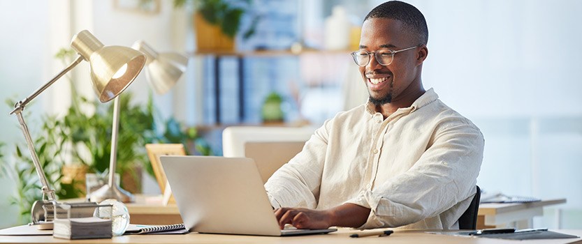 Business person using laptop at desk and smiling