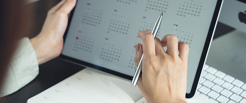 Close up of person using tablet displaying monthly calendar