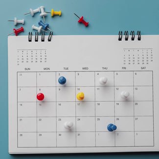 A calendar wtih push pins on various dates